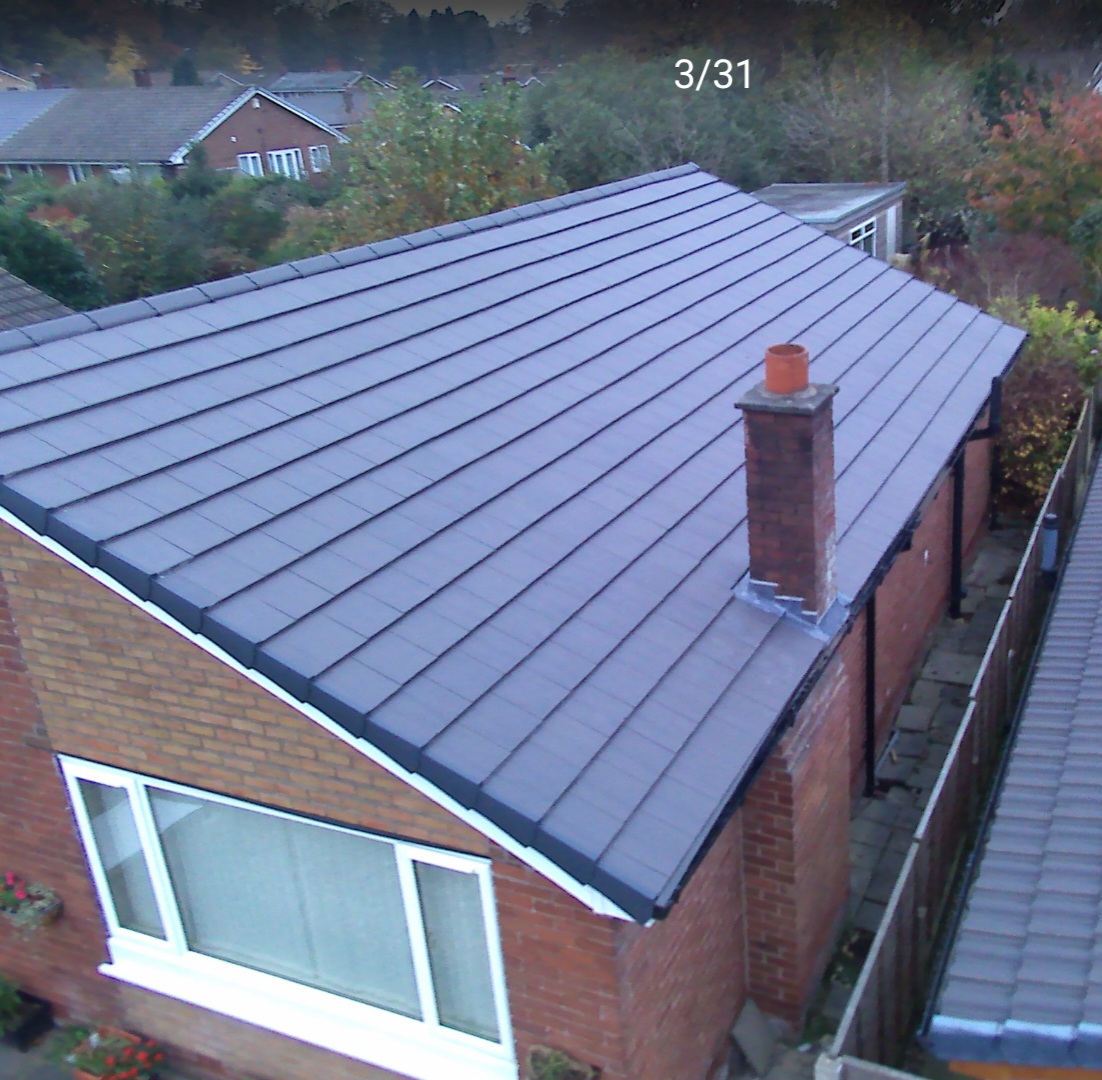 Finished anthracite tiled roof with chimney flashing on a red-brick house