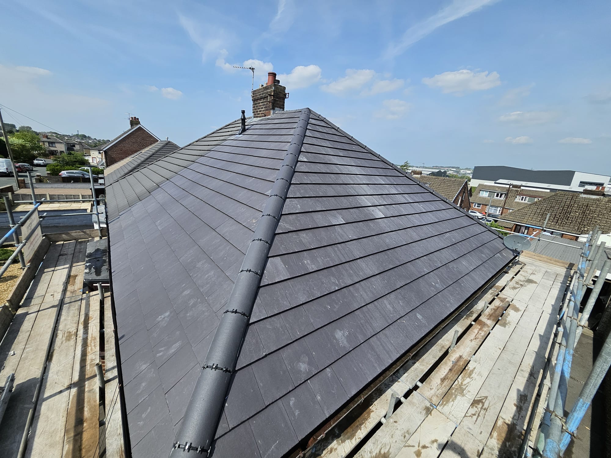 Finished dark grey tiled hip roof with matching ridge tiles and chimney